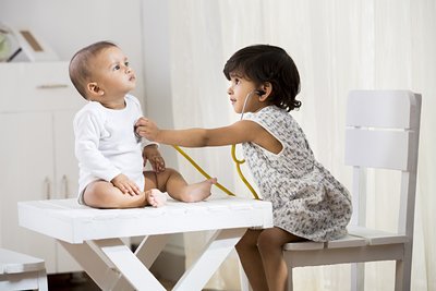 Two young children playing doctor with a stethoscope